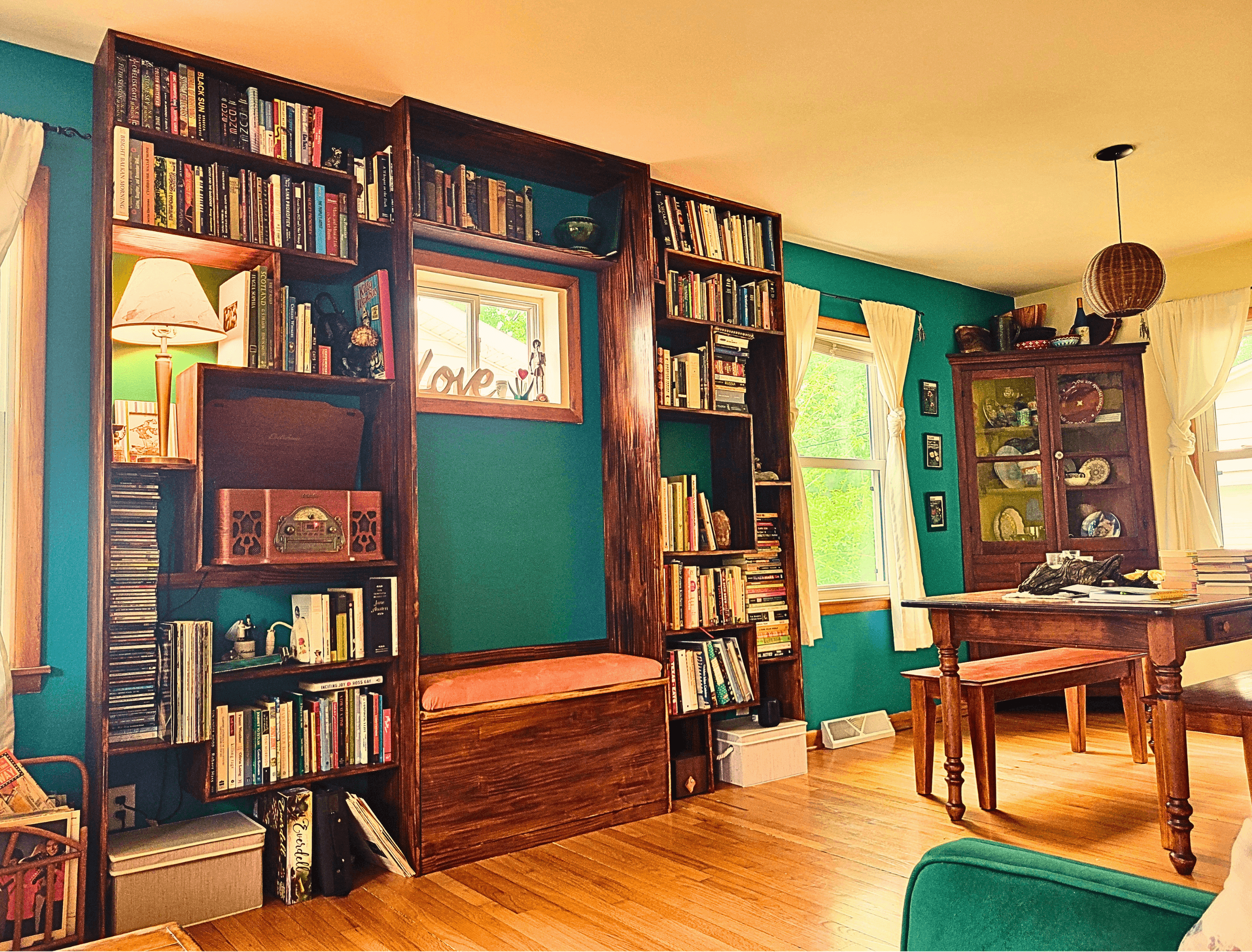 Large dark wood built-in bookshelves and a dining table in a cozy teal room.