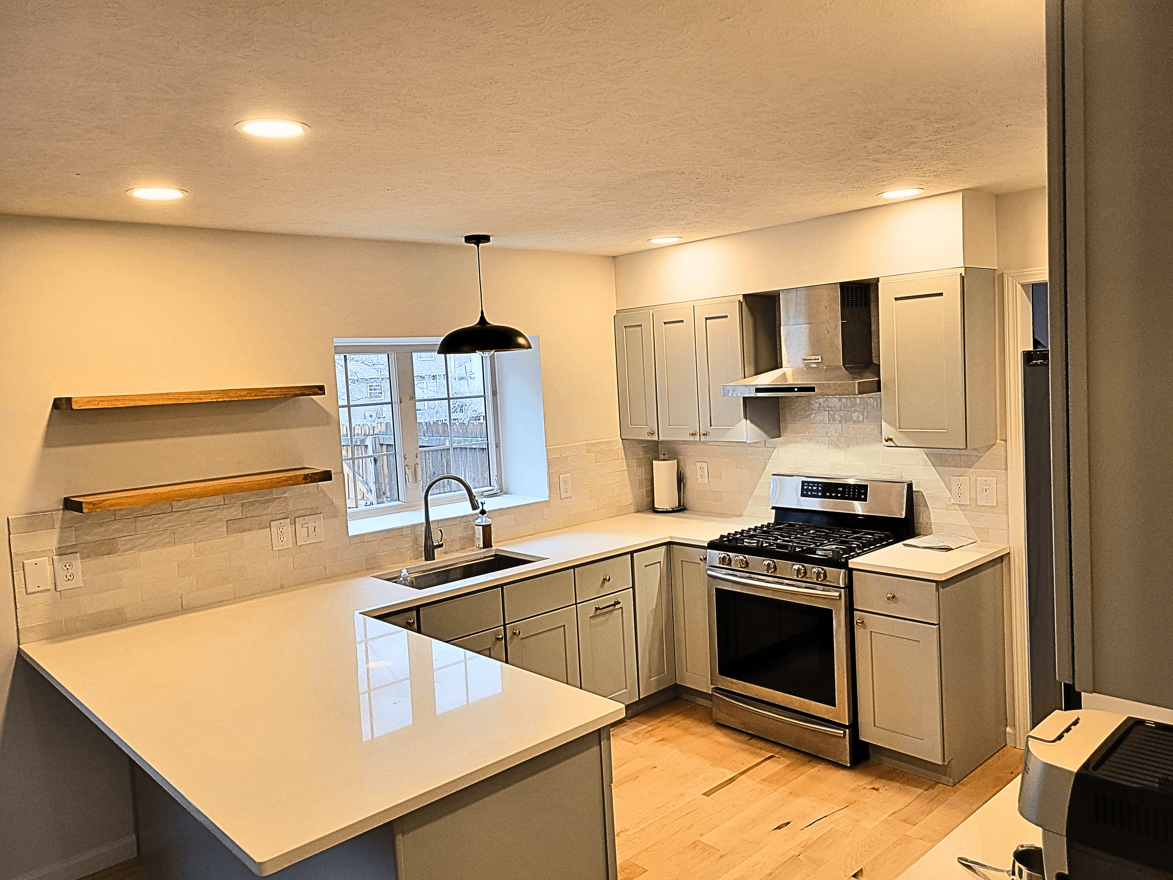 Modern kitchen featuring sage green cabinets, white quartz countertops, and stainless steel appliances.